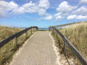 un chemin menant à la plage avec une clôture en bois dans l'établissement Kroonstuk 2, à Nes