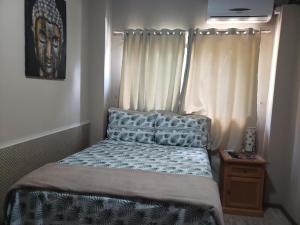 a small bedroom with a bed with a window at Plumeria Guest House in Florianópolis