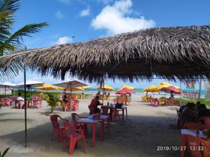 un grupo de mesas y sillas con sombrillas en una playa en Recanto das Folhas, en Paripueira