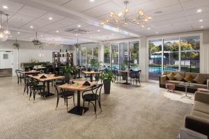 a restaurant with tables and chairs in a room with windows at Mercure Tauranga in Tauranga