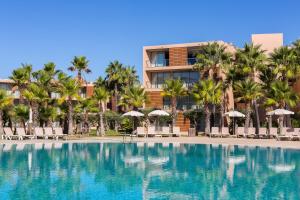 uma piscina com palmeiras e um edifício em Apartamentos Vila das Lagoas – Salgados na Guia