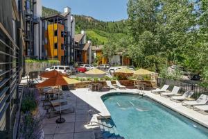 una piscina con sillas y sombrillas junto a un edificio en Durant Unit B202, Spacious Condo with Great Views, Excellent Location 2 Blocks to Ski Slopes, en Aspen