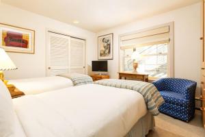 a bedroom with two beds and a chair and a television at Durant Unit B202, Spacious Condo with Great Views, Excellent Location 2 Blocks to Ski Slopes in Aspen