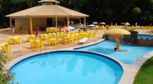 a large swimming pool with yellow chairs and a pavilion at Golden Dolphin Express in Caldas Novas