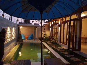a house with a swimming pool and an umbrella at Adioga Villa in Ubud