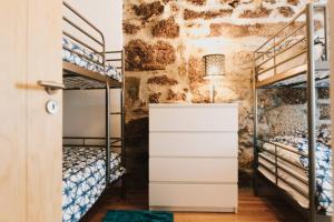 a bedroom with two bunk beds and a stone wall at Casa Oeste in Sabugueiro