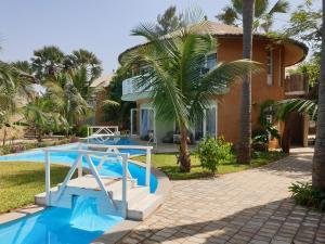 a villa with a swimming pool and a house at Balafon Beach Resort in Kololi