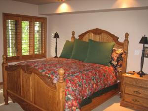 a bedroom with a large wooden bed with green pillows at JHRL - Teton Pines Townhome #20 in Wilson