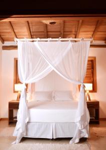 a bedroom with a bed with a canopy at Casa Pitanga - Caraíva in Caraíva