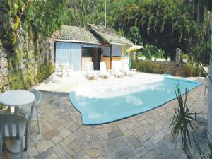 a swimming pool with a table and chairs next to a house at Casa do Joca - Ilhabela in Ilhabela