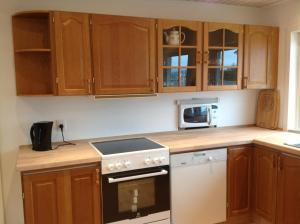 a kitchen with wooden cabinets and a stove top oven at Marna Guesthouse doubleroom nr.2 in Tórshavn