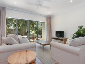a living room with two white couches and a television at Byron Beachside 8 in Byron Bay