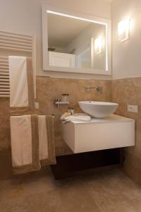 a bathroom with a sink and a mirror and towels at Baia Bianca Suites in Portoferraio