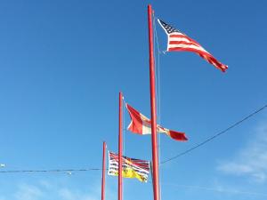 Tres banderas americanas volando en el cielo azul en Traveller's Inn, en Dawson Creek