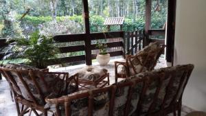 um alpendre com cadeiras e plantas e uma grande janela em Mansão Adonai nas Cachoeiras de Penedo em Penedo