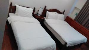 two beds in a hotel room with white pillows at 社長的家 in Luodong