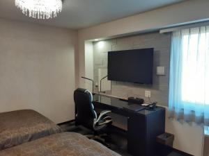 a bedroom with a desk with a television and a bed at HOTEL WIN in Imari