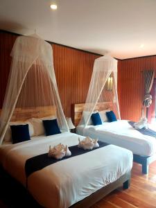 a bedroom with two beds with mosquito nets on them at Thanya Beach Resort - SHA Plus in Ko Ngai +37 photos