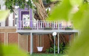 The Bayview Hotel Pattaya في باتايا سنترال: منزل وسطح أرجواني بجوار شجرة