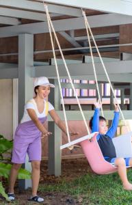 Eine Frau und ein Junge spielen auf einer Schaukel in der Unterkunft The Bayview Hotel Pattaya in Pattaya