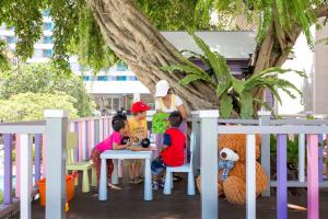 een groep kinderen die aan een tafel onder een boom zitten bij The Bayview Hotel Pattaya in Pattaya