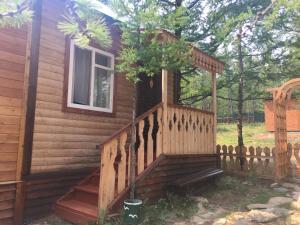 a wooden cabin with a porch and a fence at Guest House Muhtuya in Sarma