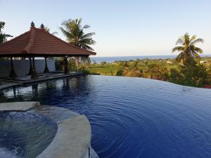 una piscina con cenador y el océano en Bali Nibbana Resort, en Umeanyar