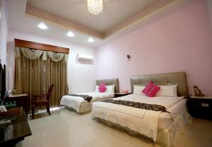 a bedroom with two beds with pink pillows at GuiZhuLin B&B in Jiaoxi