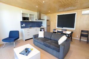 Waikanae Beach Ocean View Apartments في جيسبورن: غرفة معيشة مع أريكة وطاولة ومطبخ