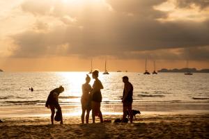 a group of people standing on the beach at sunset at Royal Lanta Resort & Spa in Ko Lanta