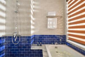 a blue tiled bathroom with a tub and a shower at Sofiana My Khe Hotel & Spa- Rooftop Pool Bar in Danang