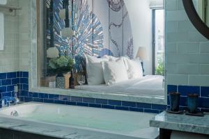 a bathroom with a bed with a mirror and a tub at Sofiana My Khe Hotel & Spa- Rooftop Pool Bar in Danang