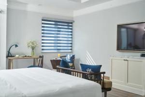 a bedroom with a bed and chairs and a television at Sofiana My Khe Hotel & Spa- Rooftop Pool Bar in Danang