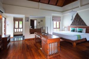 a bedroom with a large bed and a desk with a television at Royal Lanta Resort & Spa in Ko Lanta