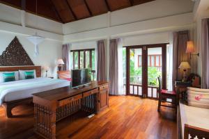 a bedroom with a bed and a desk with a television at Royal Lanta Resort & Spa in Ko Lanta