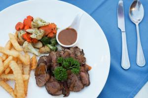 a white plate of food with french fries and meat at Royal Lanta Resort & Spa in Ko Lanta