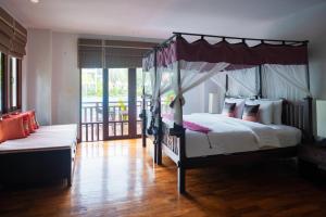 a bedroom with a four poster bed and a balcony at Royal Lanta Resort & Spa in Ko Lanta