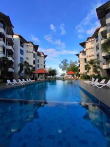a swimming pool in a resort with chairs and buildings at Samsuria Private Beach Front in Kuantan