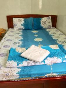 a bed with a blue comforter with a book on it at Guesthouse Minh Thu in Ho Chi Minh City