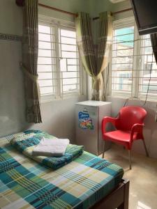 een slaapkamer met een bed en een rode stoel bij Guesthouse Minh Thu in Ho Chi Minh-stad