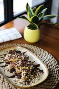 a plate of dessert on a table with a potted plant at Kama Hotel in Medan