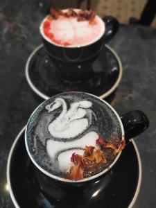 two cups of cappuccino and a cake on a table at Kama Hotel in Medan
