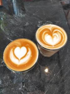 two cups of cappuccinos sitting on a table at Kama Hotel in Medan