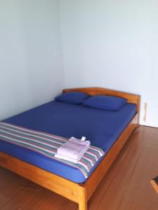 Una cama con sábanas azules y almohadas azules. en New Cottage Asri Karimunjawa en Karimunjawa