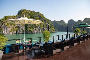 una terraza con sillas, mesas y sombrilla en Rosy Cruises, en Ha Long