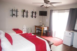 una camera da letto con un letto con coperte rosse e una scrivania di Triginta a Bloemfontein