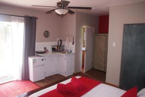 a room with a kitchen and a bed with red pillows at Triginta in Bloemfontein