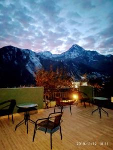 een groep stoelen en tafels op een balkon met bergen bij UP in Kazbegi