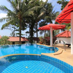 ein großer Pool mit einem roten Regenschirm und Palmen in der Unterkunft Top Resort in Ko Chang
