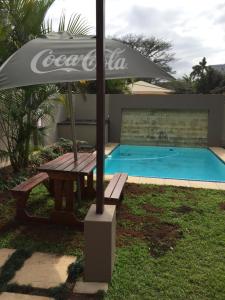 a picnic table with an umbrella next to a pool at Stylish modern 2 bed apartment in Shaka's Rock in Ballito